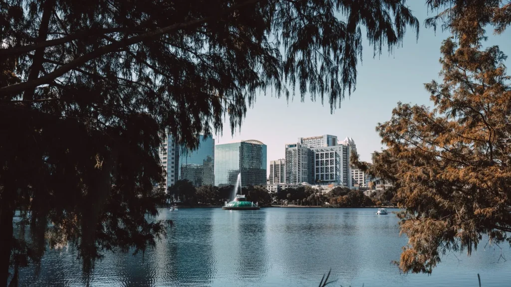 Orlando belvárosának látképe a Lake Eola tó felől, fák között